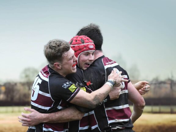Rugby players celebrating against a backdrop of a field