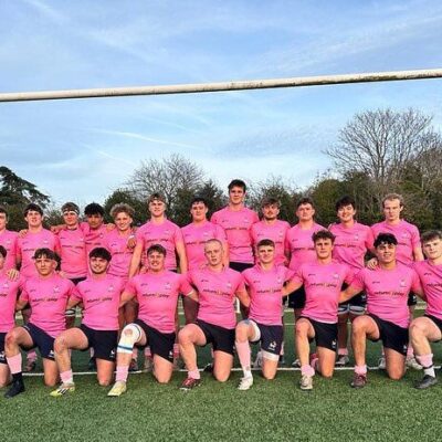 lambs rugby team lined up in 2 rows under rugby posts